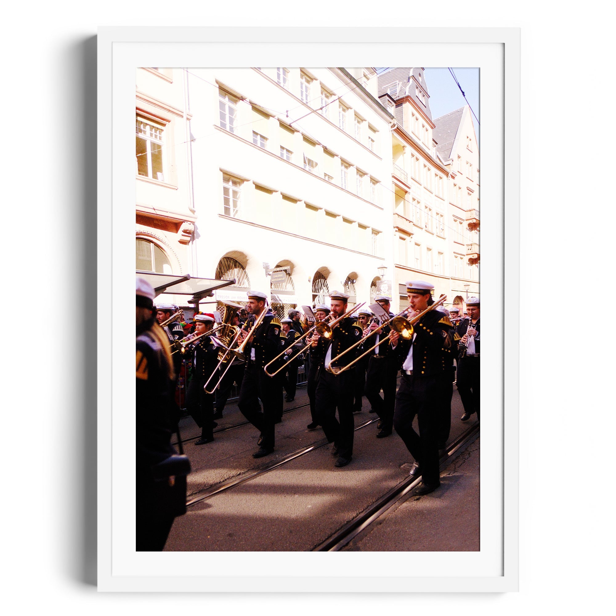 Framed fine art photograph of a marching band with trombonists parading in a historic street scene.