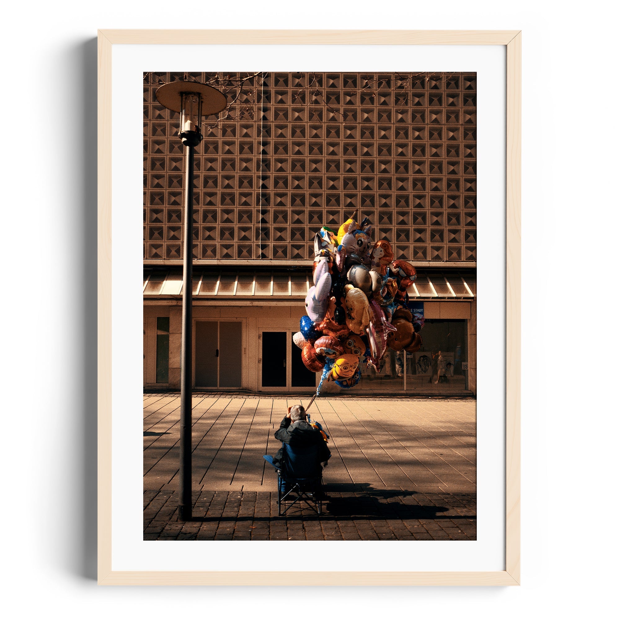 Framed fine art photograph of a person with colorful balloons against a textured building by Marcelo Cadavid at The Dana Gallery, Miami.