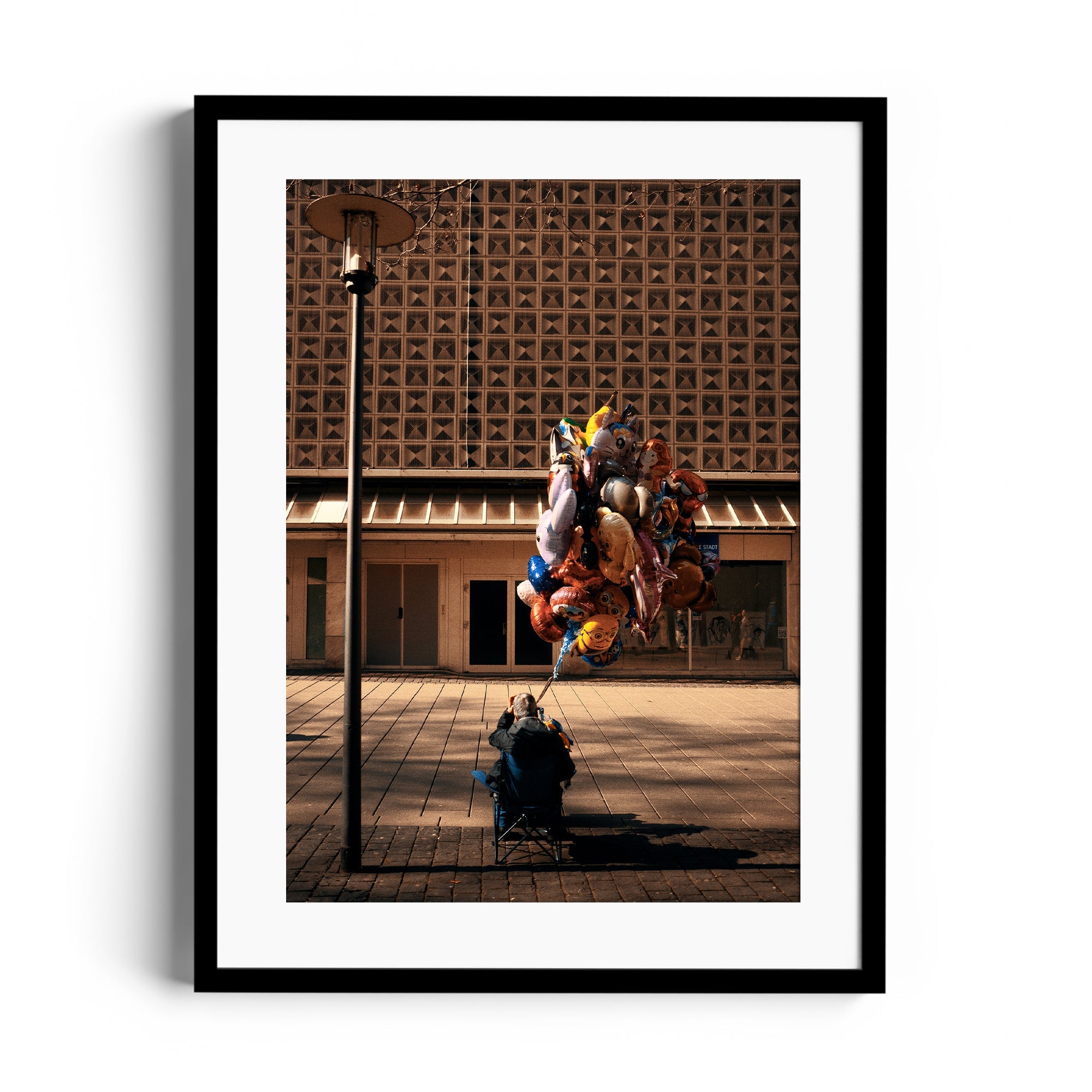 Framed fine art photograph featuring a man with colorful balloons in an urban setting, by Marcelo Cadavid.