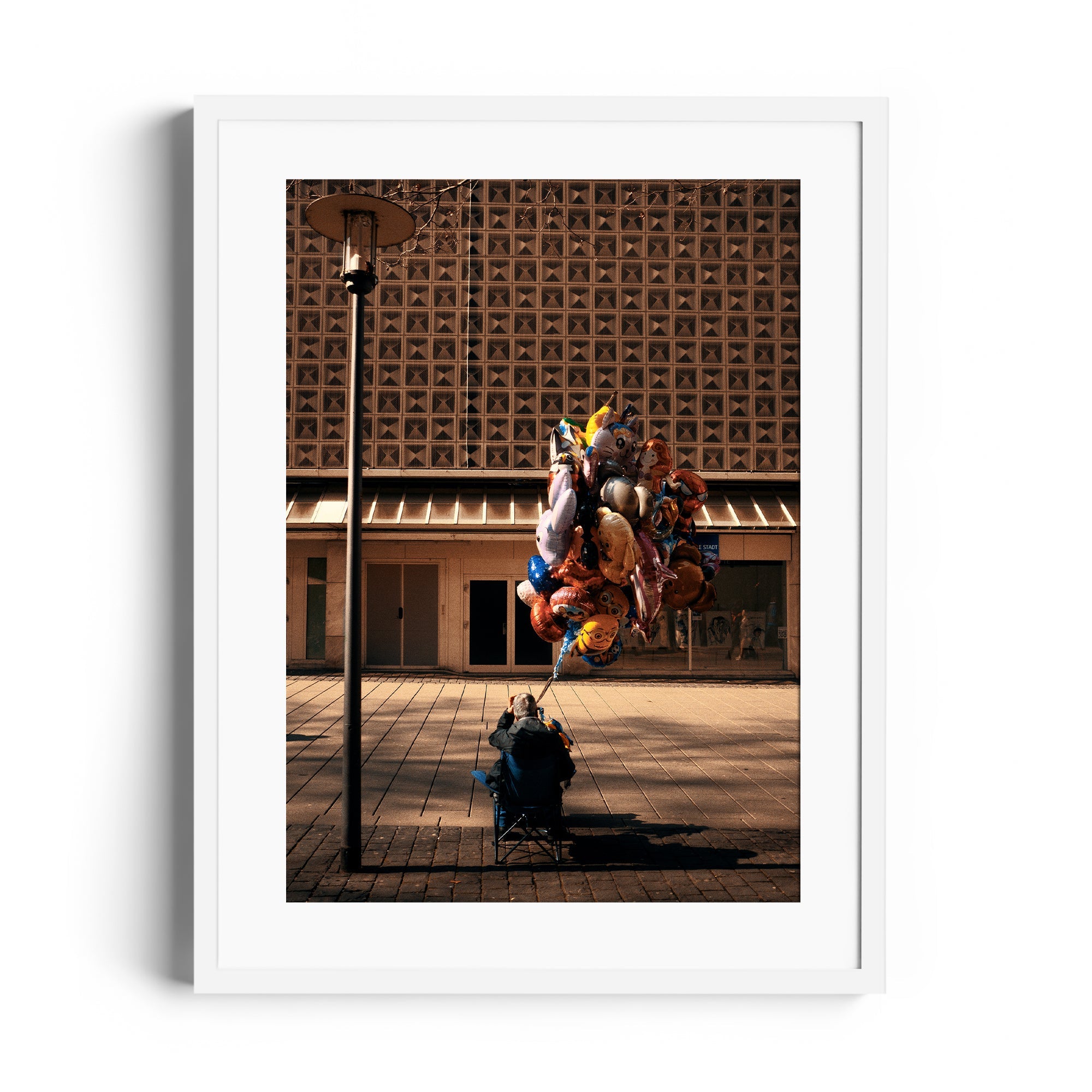 Framed fine art photograph depicting a figure with colorful balloons on a city street, available at The Dana Gallery, Miami, Florida.