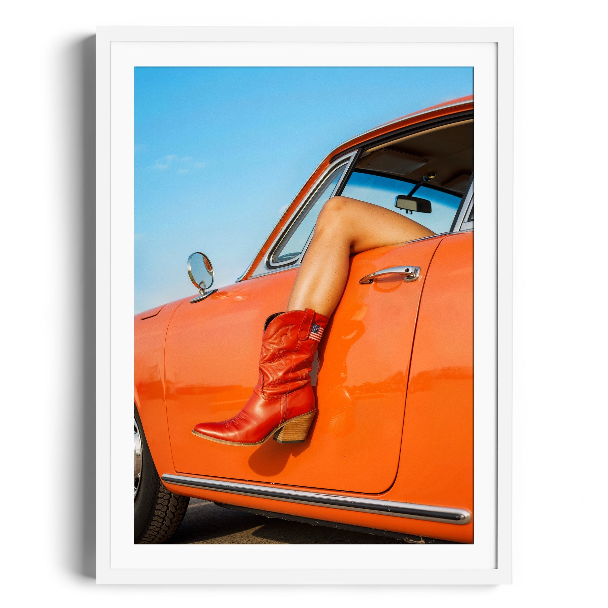 Red cowgirl boots resting on the door of an orange car, showcasing stylish footwear in a vibrant setting.