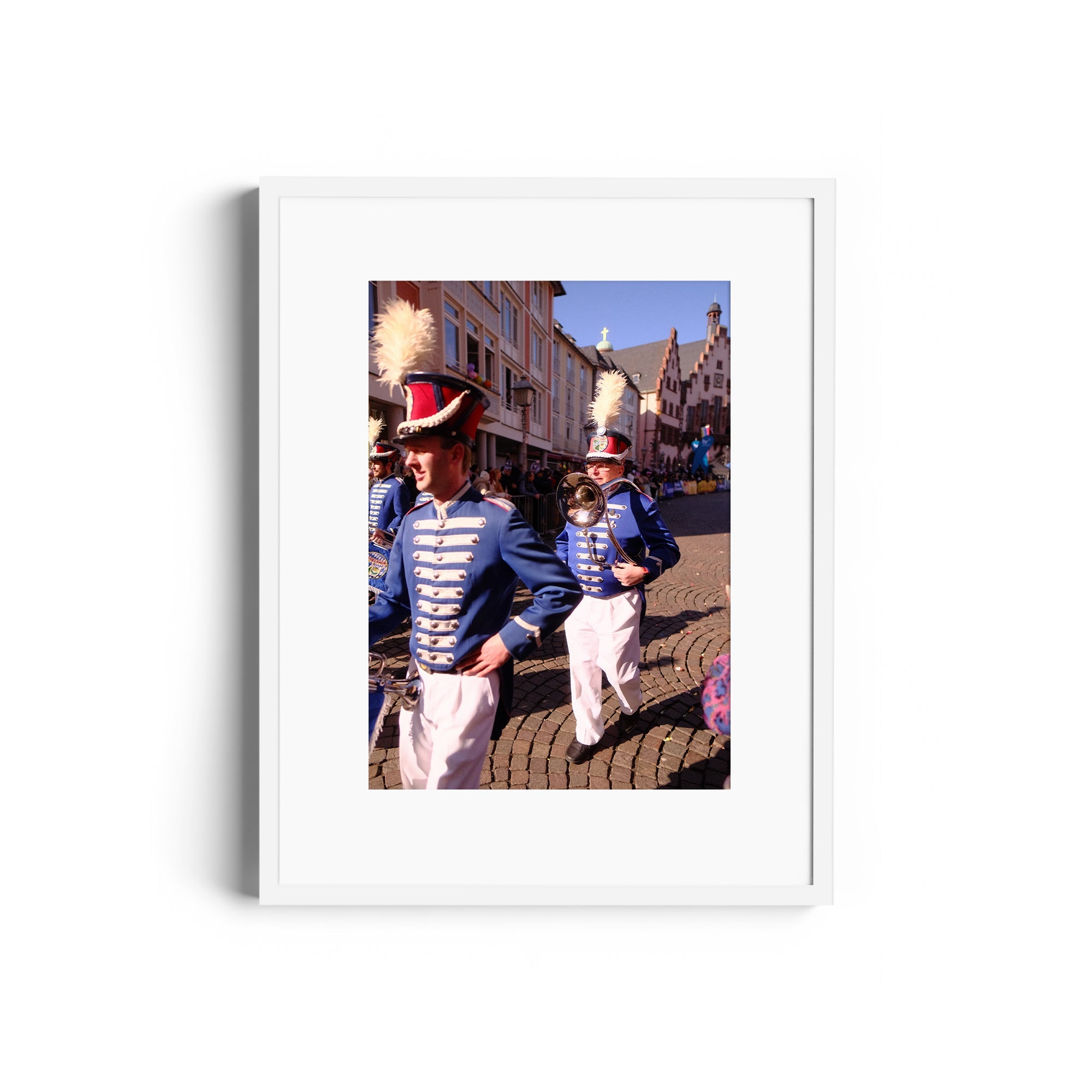 Marching band members in blue uniforms parade through a historic street, framed fine art photography from The Dana Gallery.