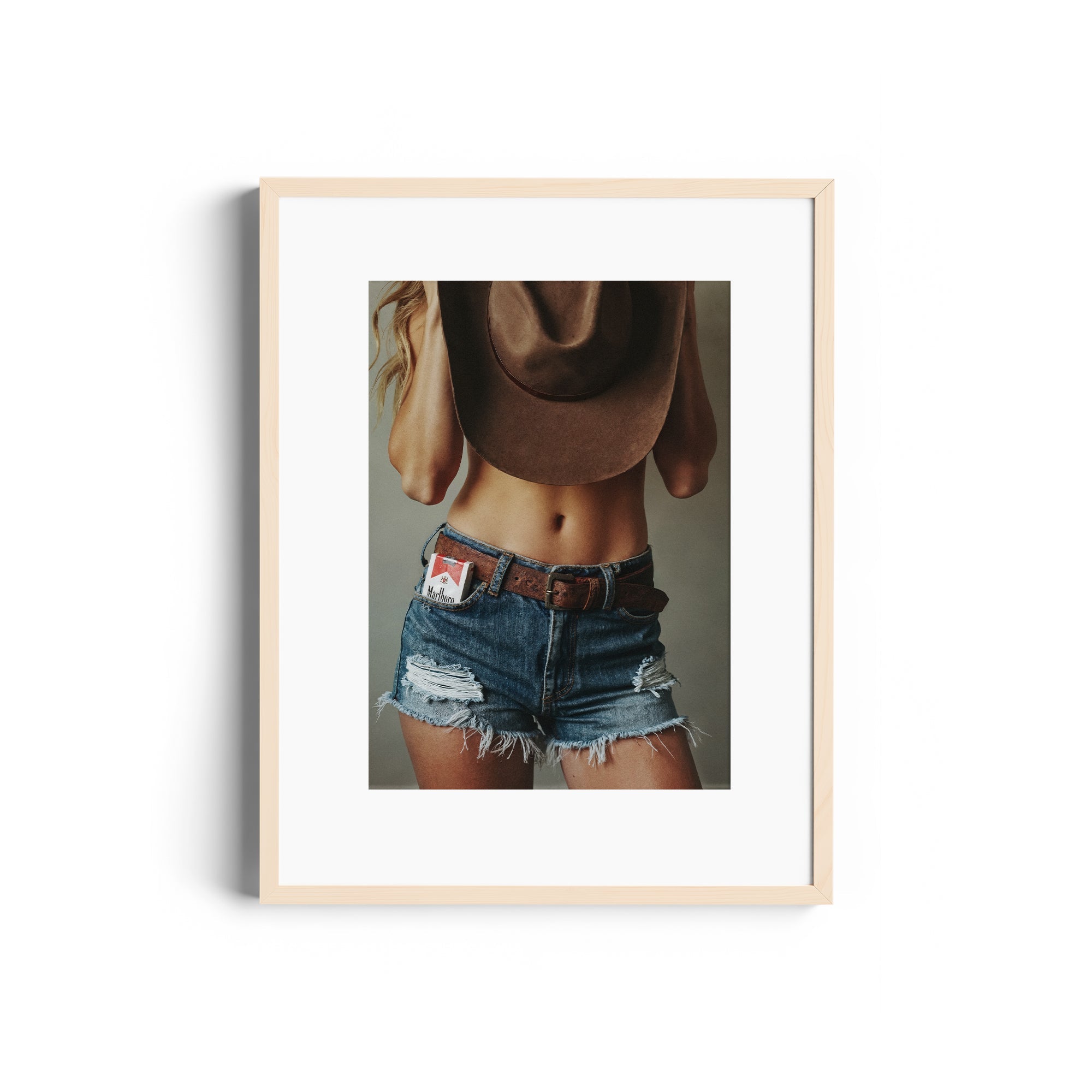 Framed fine art photography of a woman wearing denim shorts and a cowboy hat, showcasing Miami's bold style.