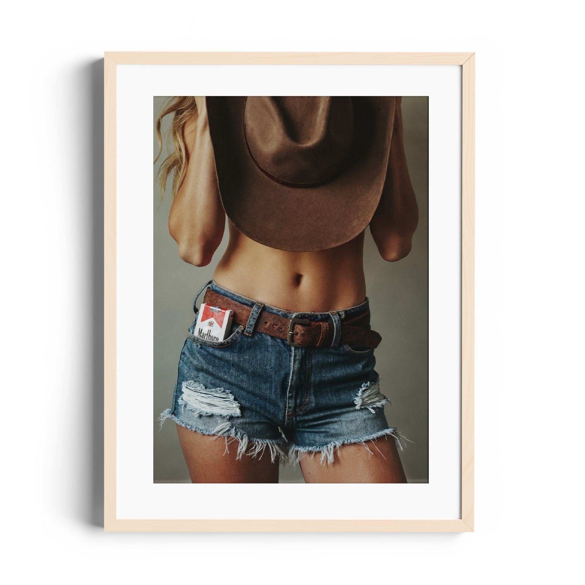 Limited edition fine art photography featuring a woman in denim shorts and a cowboy hat, showcasing a bold, independent style.