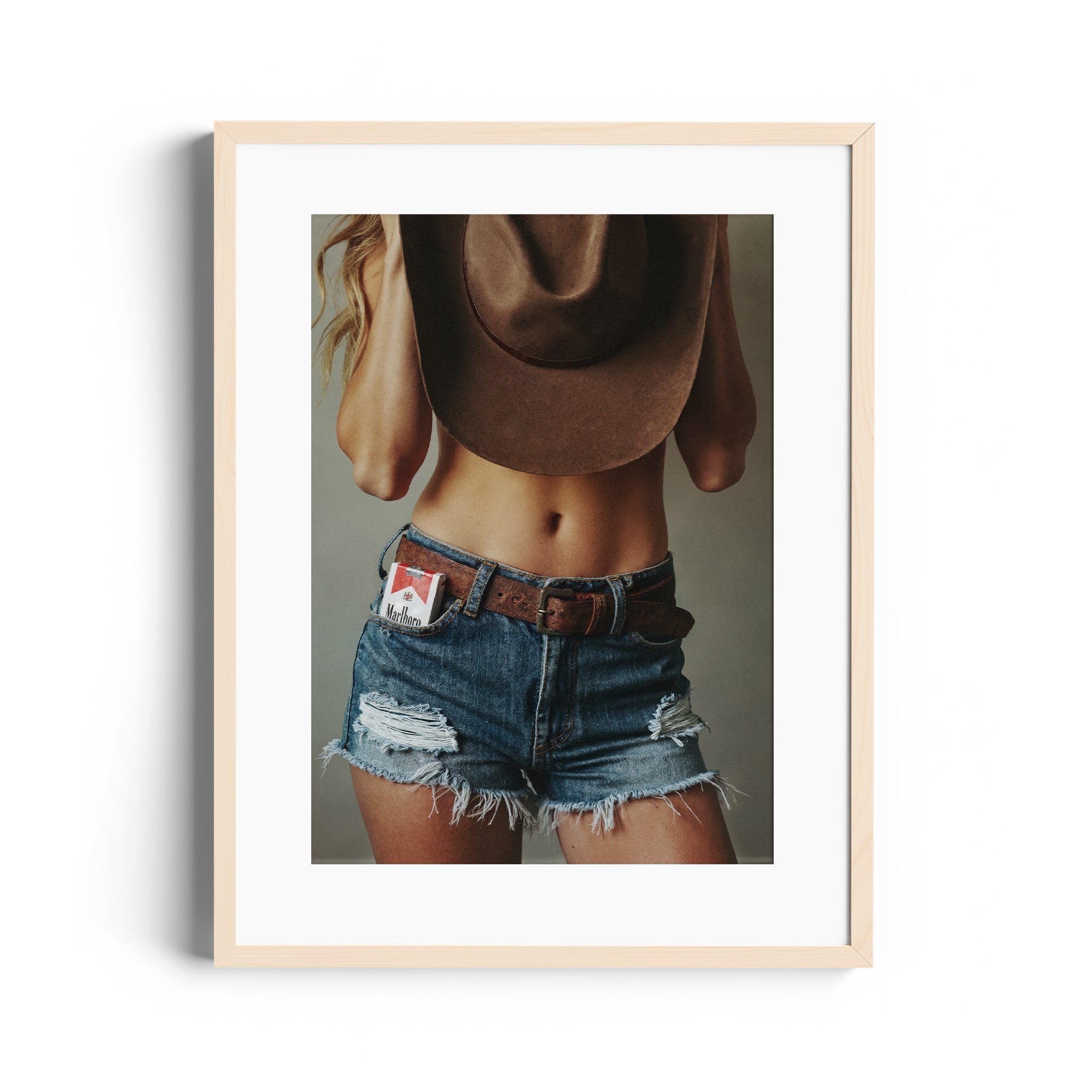 Limited edition fine art photography of a woman in distressed denim shorts and cowboy hat, print art for gallery in Miami.