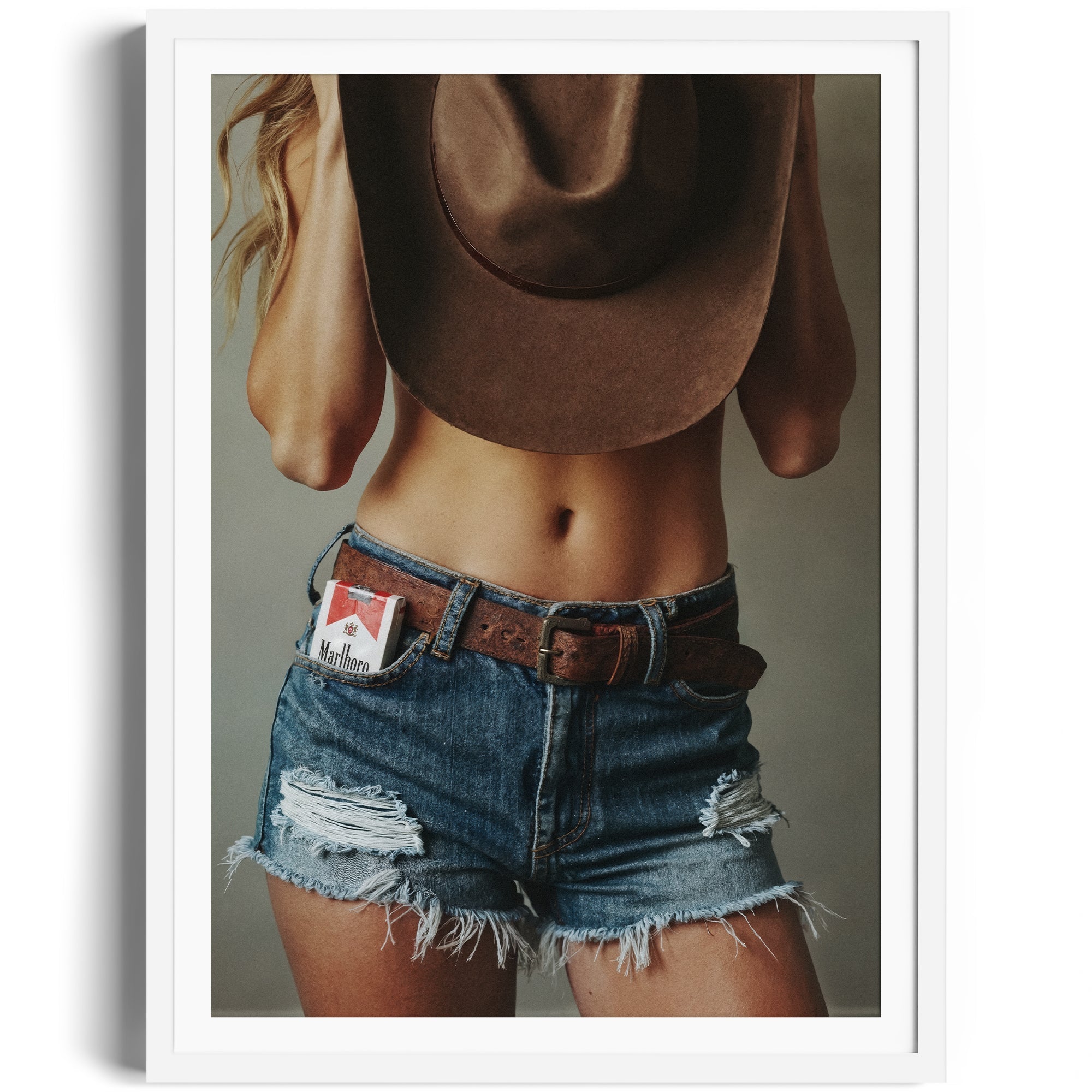 Limited edition fine art photography of a woman in distressed denim shorts and a cowboy hat, showcasing Western allure.
