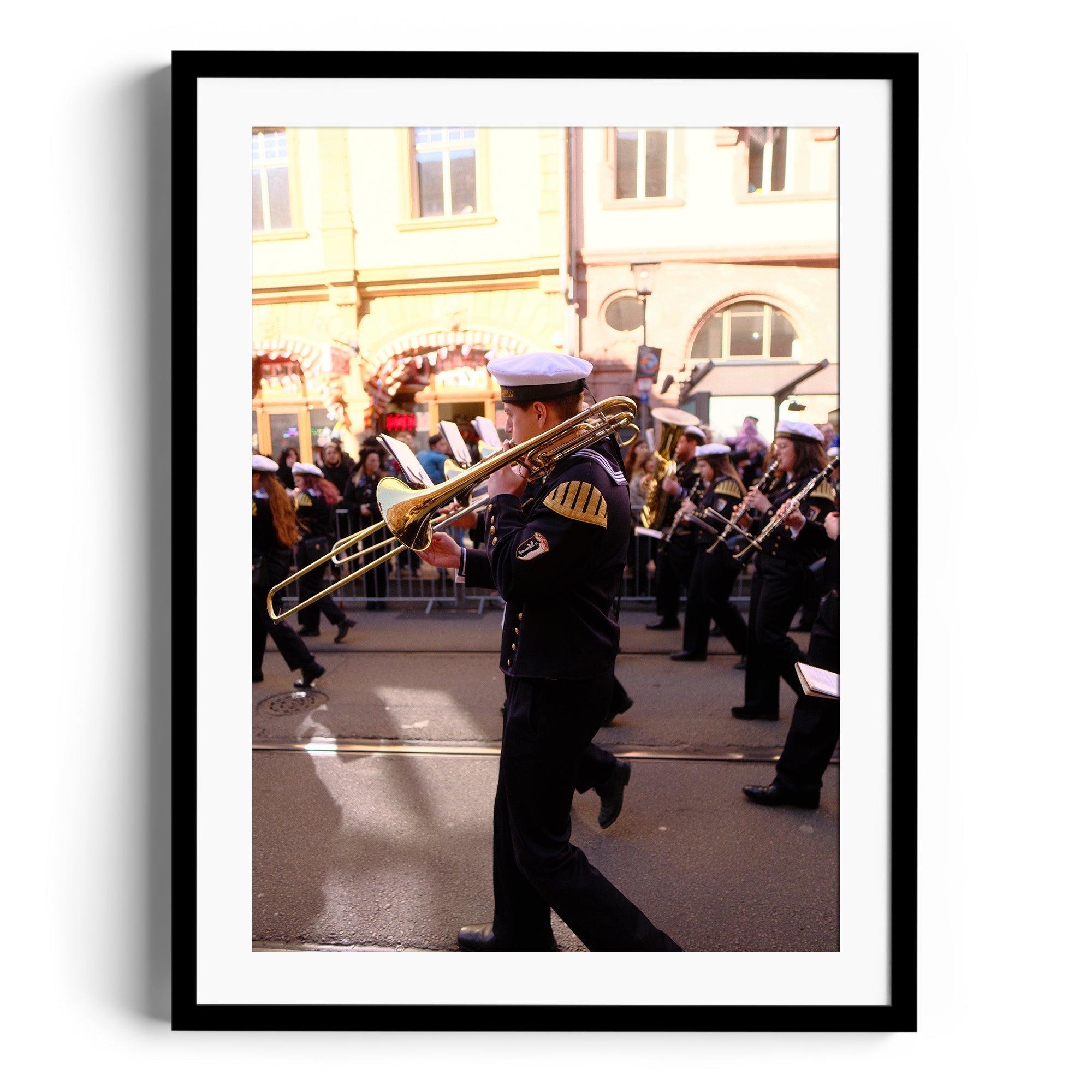 Framed fine art photograph of a musician playing trombone during a parade, capturing dynamic movement and energy.