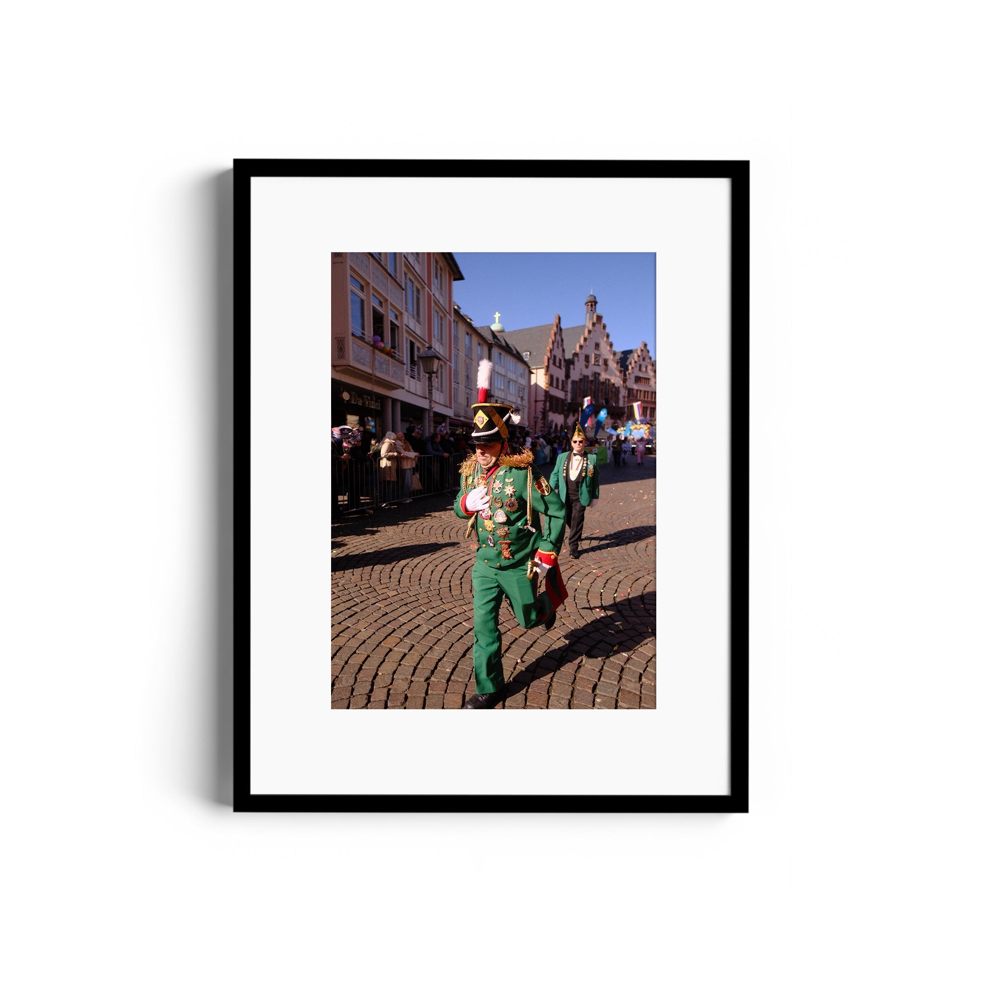 Colorful parade scene featuring marching performers in green uniforms on cobblestone street, framed fine art photography.