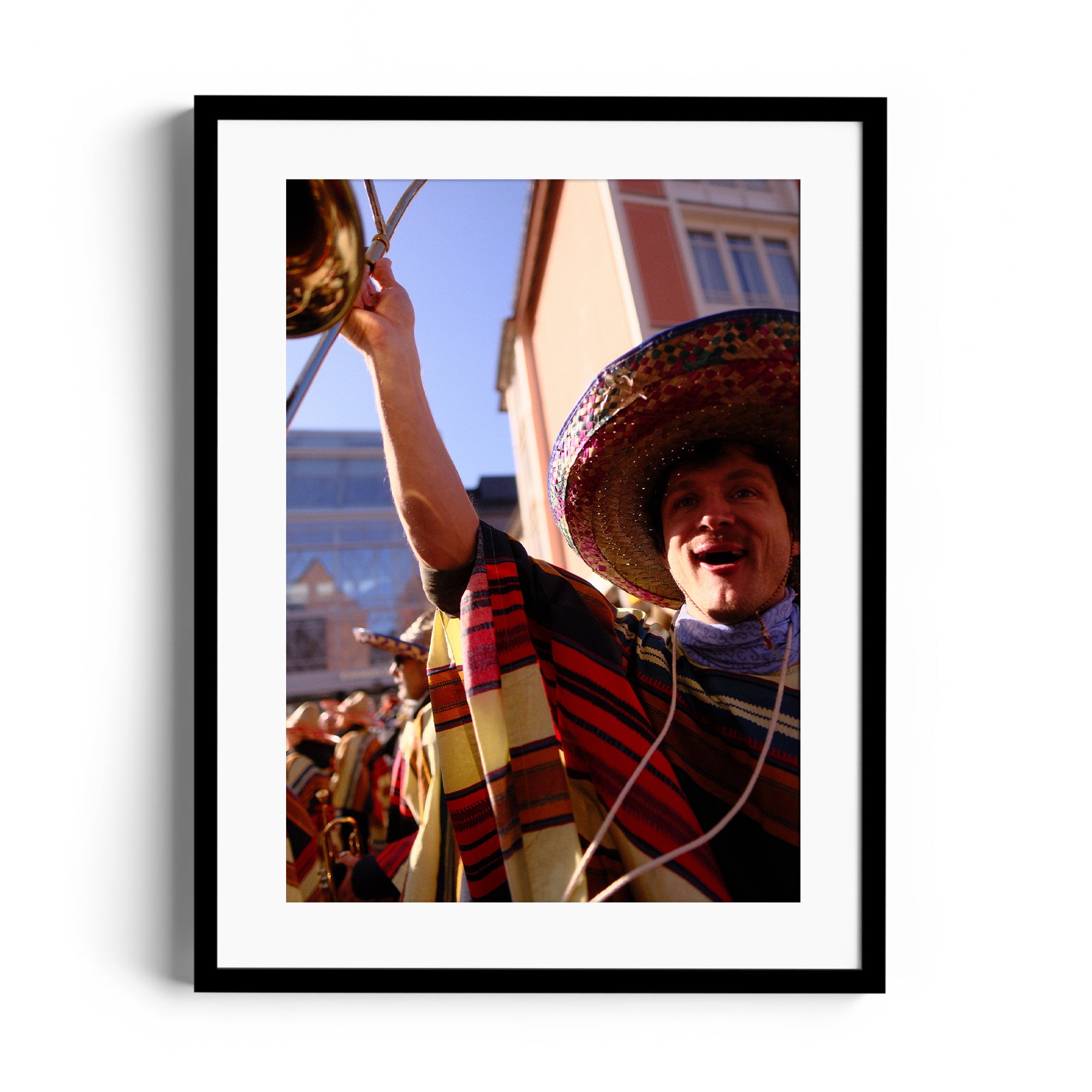 Smiling mariachi musician in colorful attire holding a brass instrument, framed fine art photography by Marcelo Cadavid.