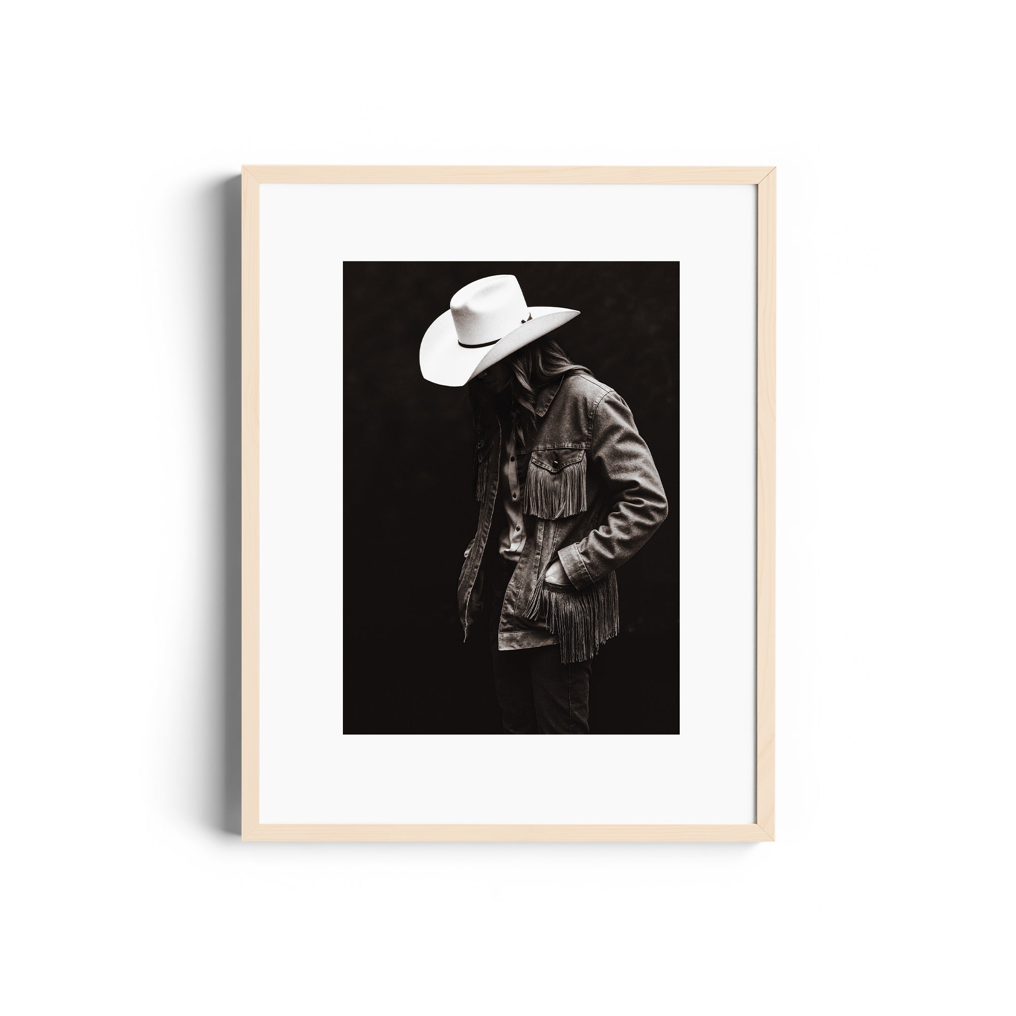 Monochromatic portrait of a lone figure in a fringed denim jacket and cowboy hat, representing Western spirit in fine art.