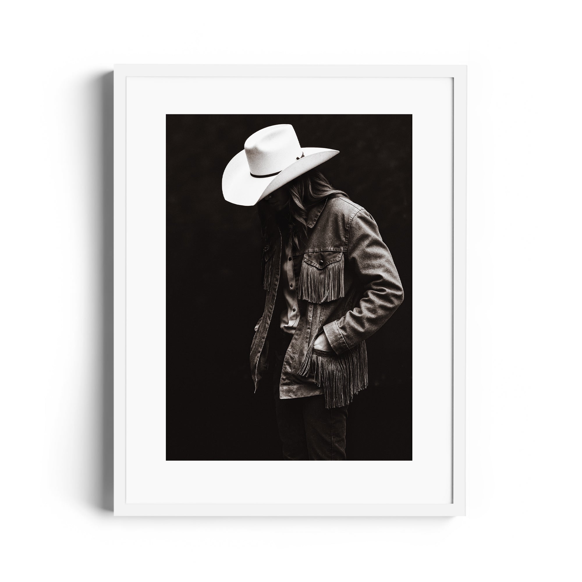 Monochromatic fine art photograph of lone figure in fringed denim jacket and cowboy hat, capturing Western spirit.