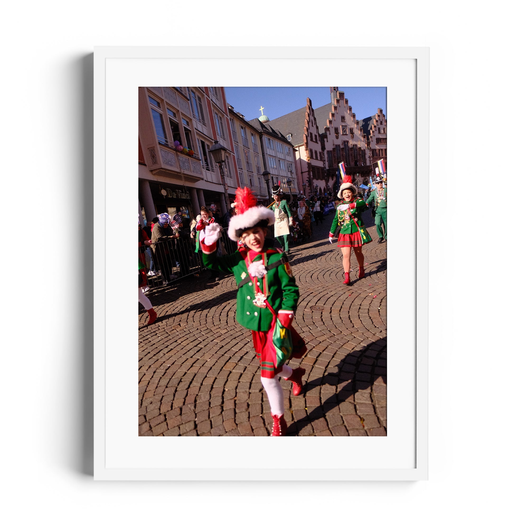 Festive parade scene featuring children in green holiday costumes celebrating in a cobblestone street.