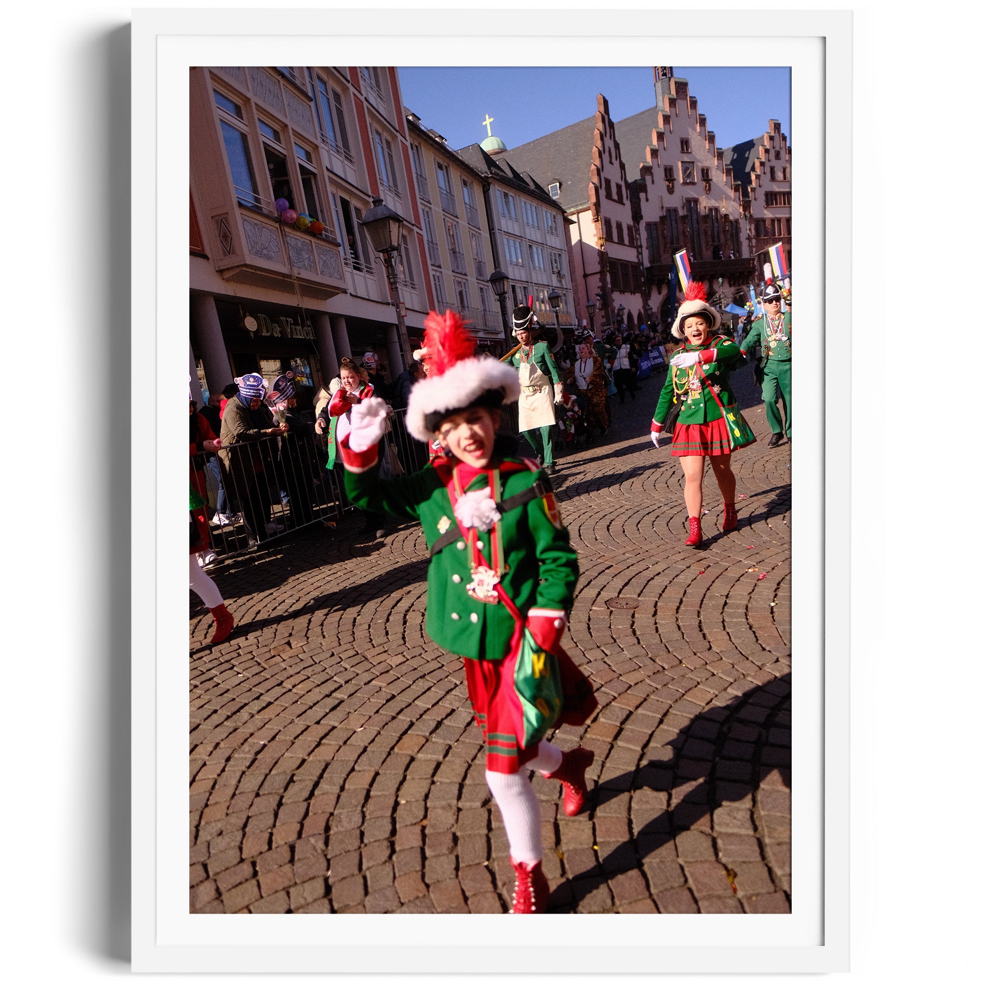 Colorful parade scene featuring joyful performers in festive attire on cobblestone street.