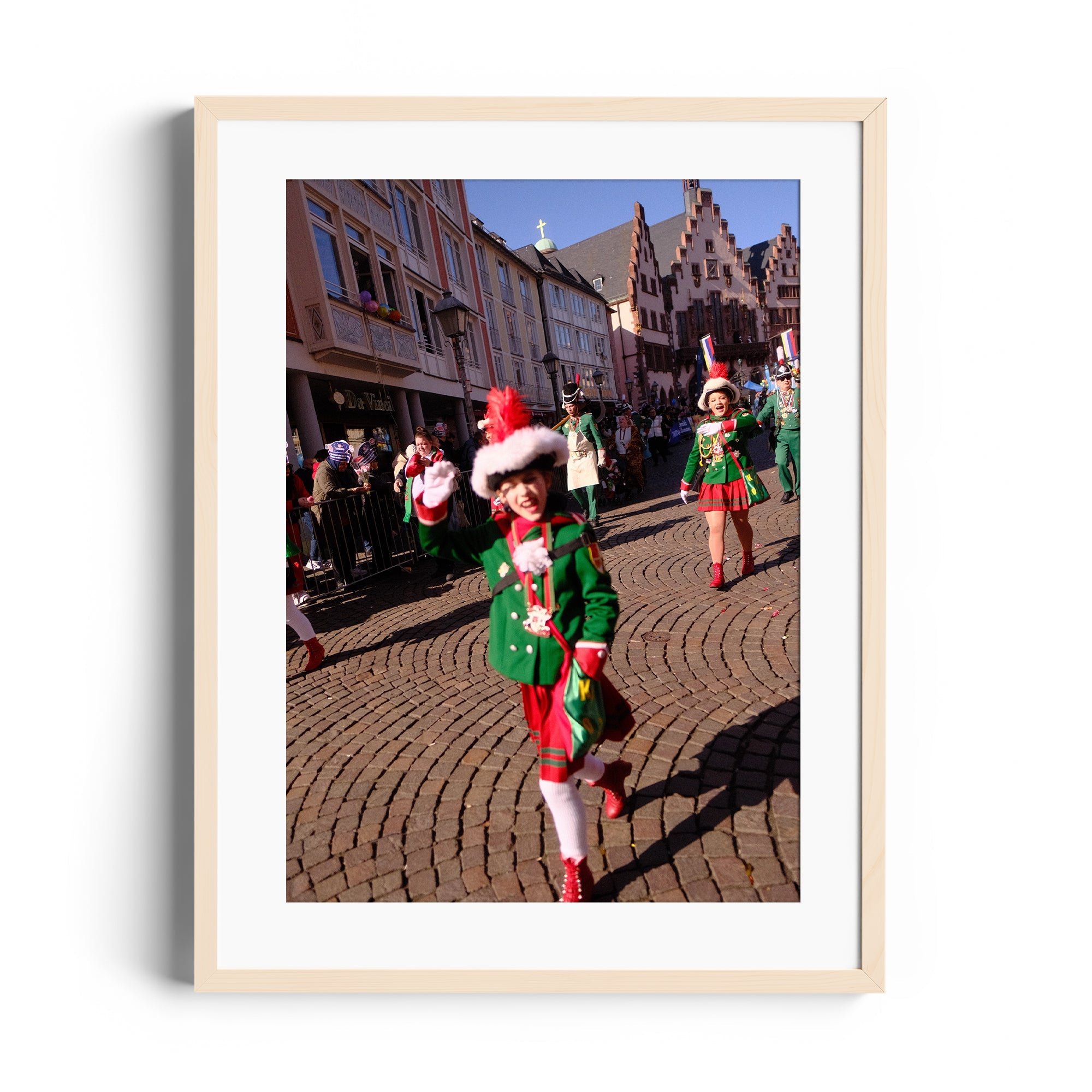 Children in festive costumes parade through a cobblestone street, celebrating with joy and holiday spirit.